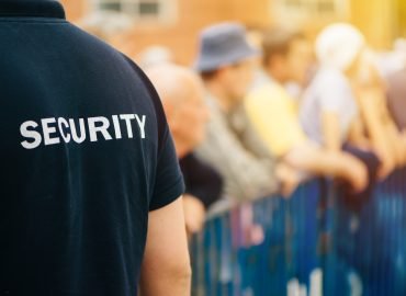 Member of security guard team working on public event, unrecognizable male person from behind